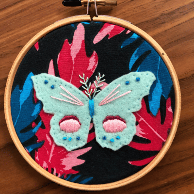 Sample of a felt embroidered butterfly on colorful leaf pattern fabric