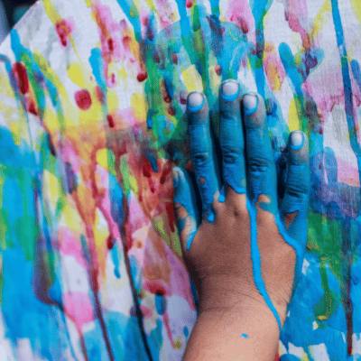 Variety of splatter paint colors and a had painted blue adding more paint to the project.