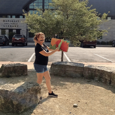 Miss Emily reading a Dinosaur book at the Village Square Park