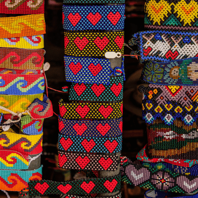 A large variety of woven beaded bracelets with heart, wave, and other designs.